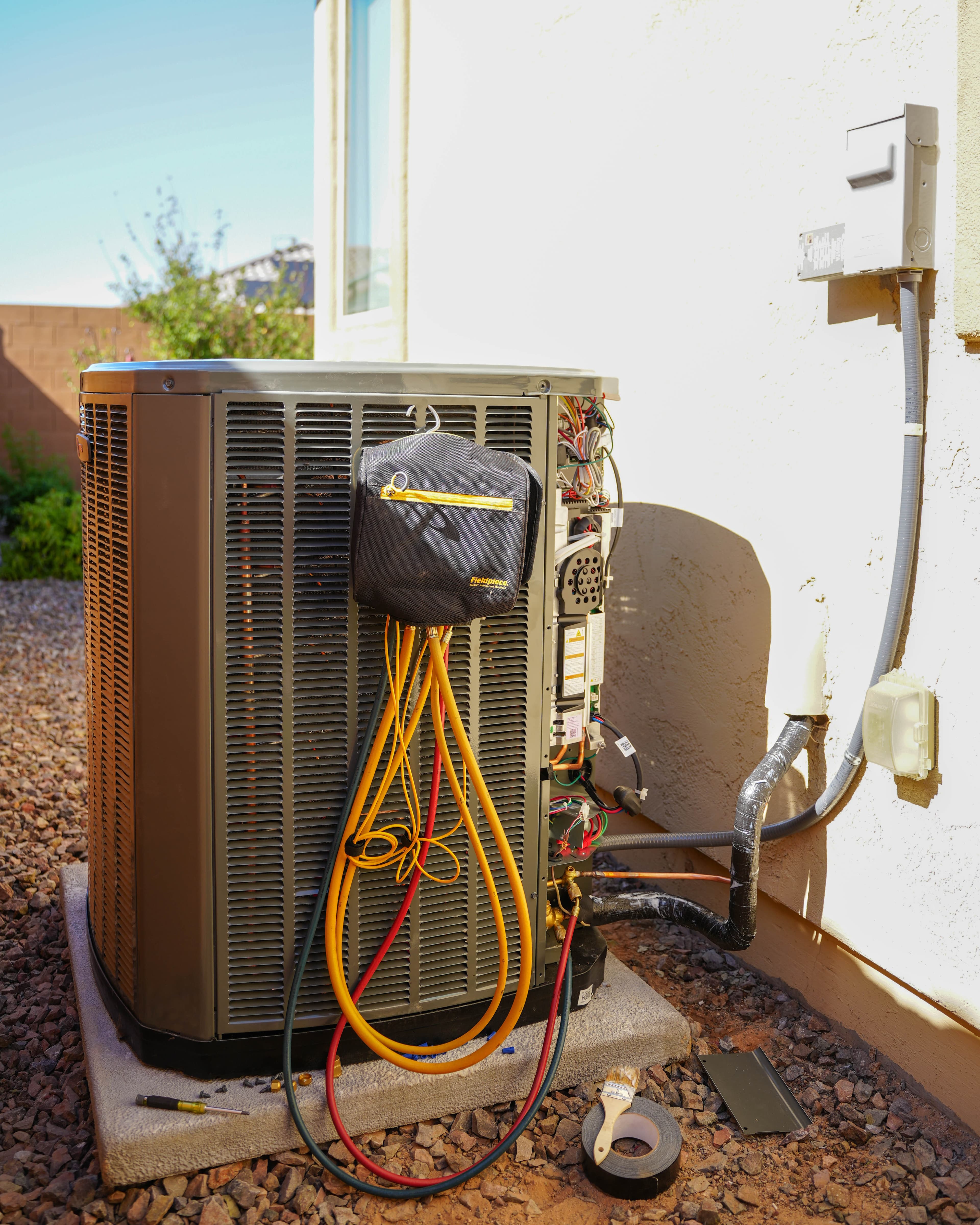 Residential air conditioning condenser unit on the side of a Goodyear stucco home